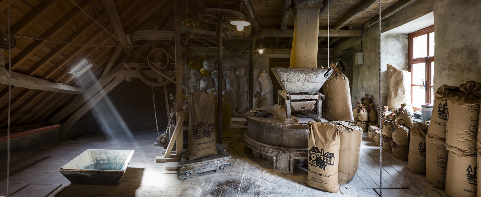 Intérieur de la meunerie du Moulin de Hollange, sacs de farine et meule